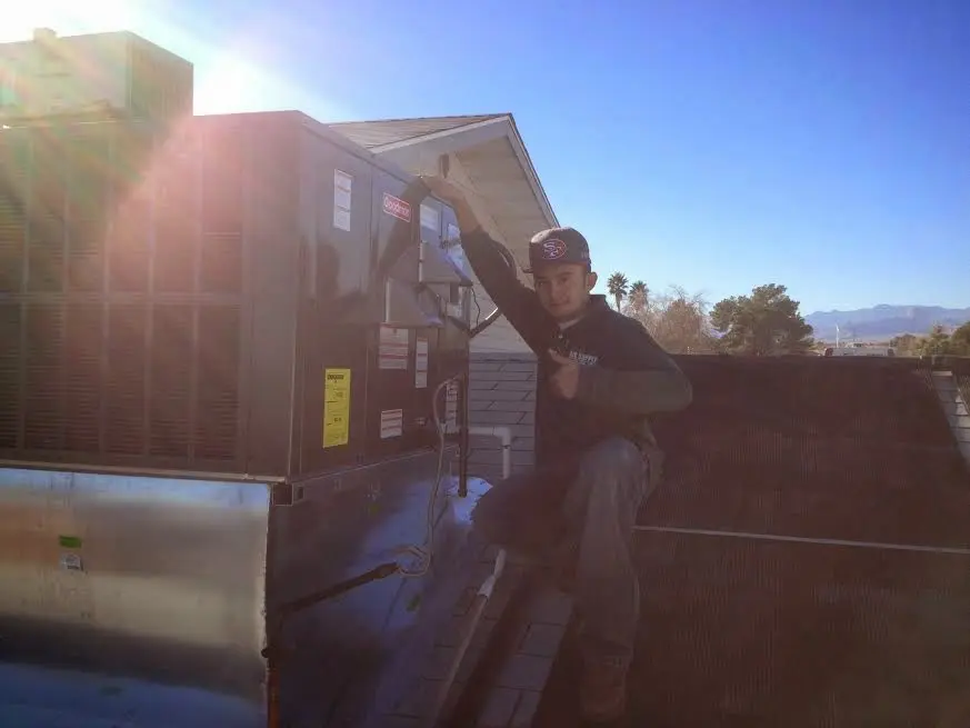 HVAC technician performing AC Tune-Up on a rooftop unit in Heartland